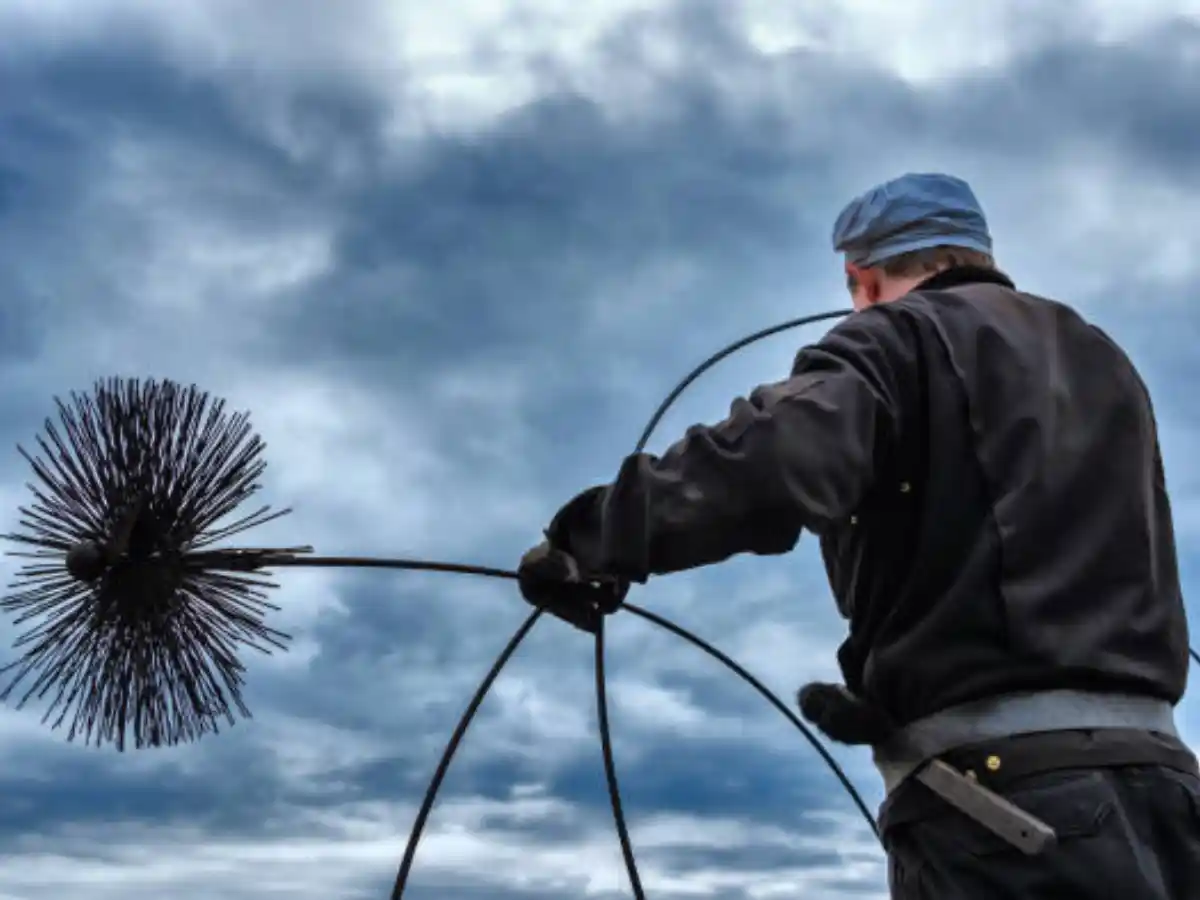 Sweep brushing a flue from the roof