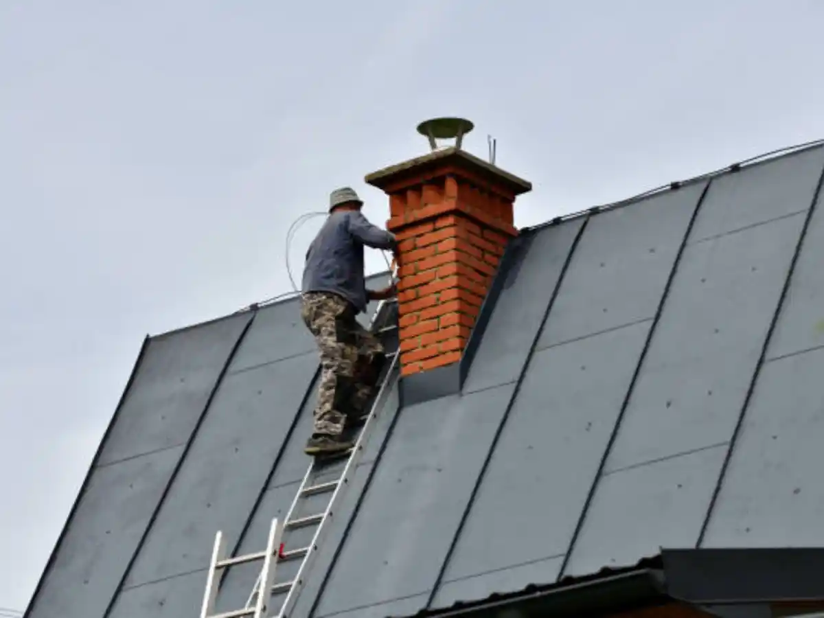 Technician sweeping a rooftop chimney